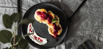 Tasty pancakes topped with fresh berry sauce on a ceramic plate, perfect for a gourmet breakfast.