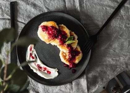 Tasty pancakes topped with fresh berry sauce on a ceramic plate, perfect for a gourmet breakfast.
